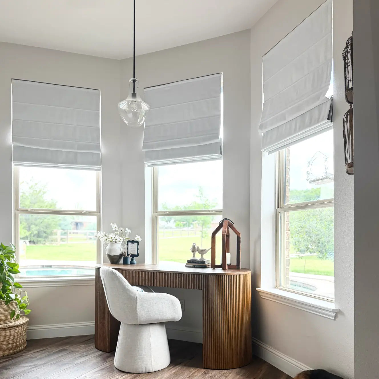 Modern home office with wooden desk, white chair, and large windows.