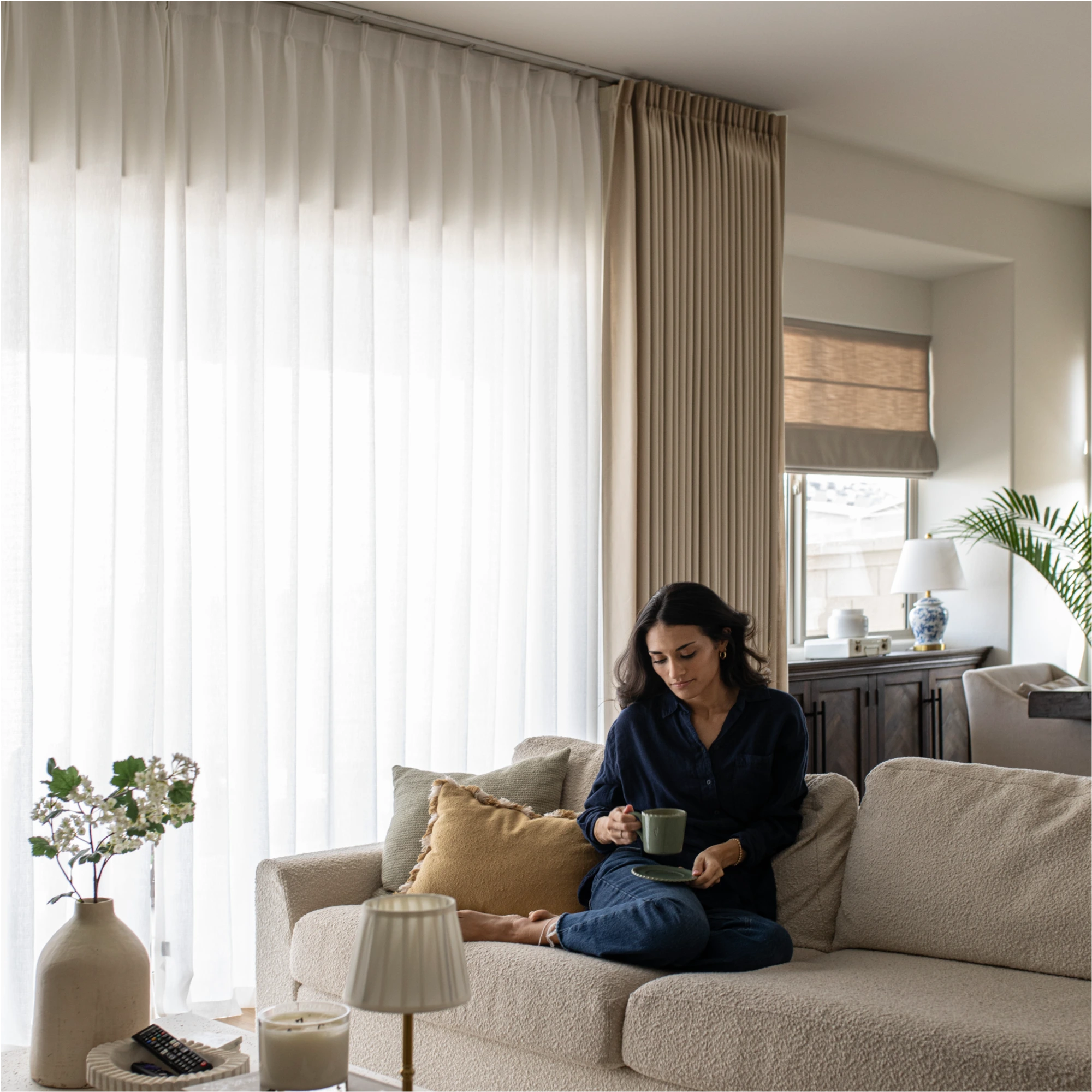 Ilythra cotton curtains main image in a living room with a person seated on a sofa, showing soft drape and natural light filtering ambiance
