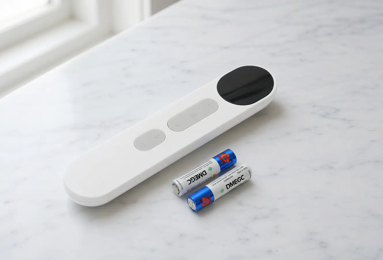 White electronic device with a black circular component on a marble surface, accompanied by two batteries.