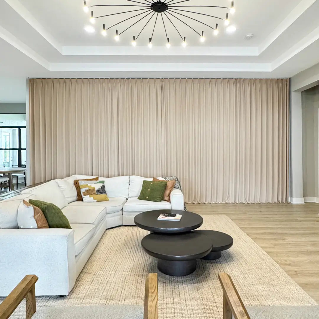 Translation missing: en.Modern living room with a white sectional sofa, dark coffee table, and large curtains