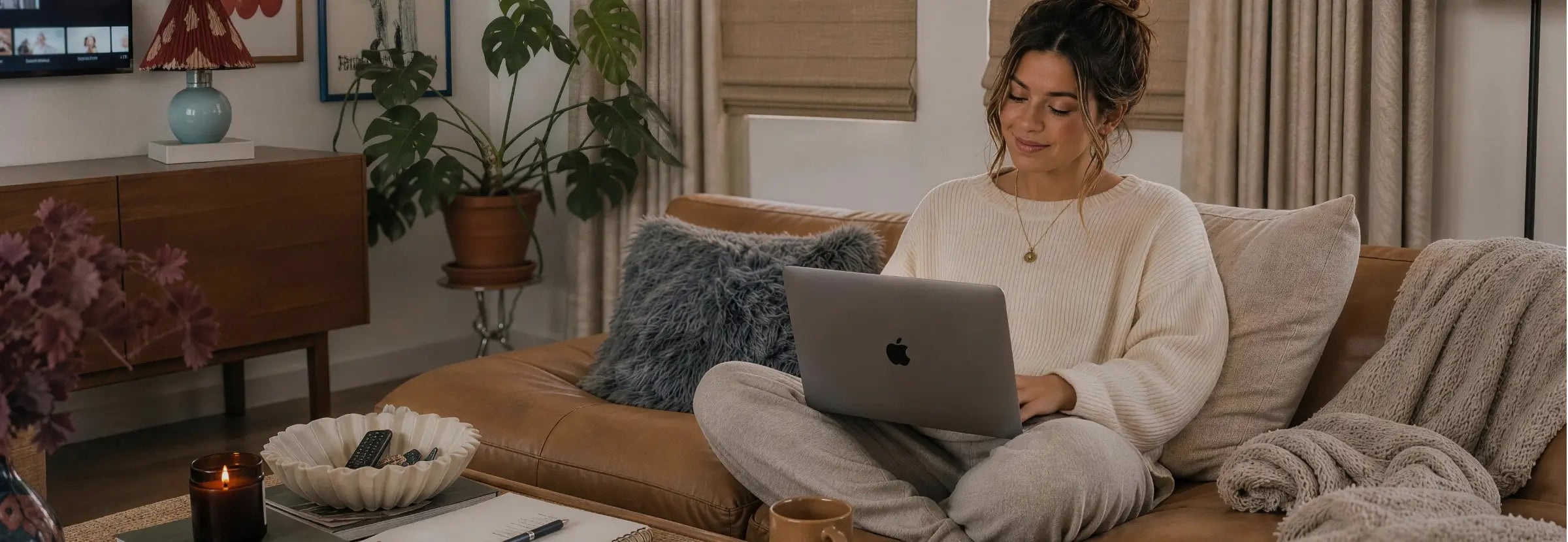 Woman using a laptop on a couch in a cozy living room.
