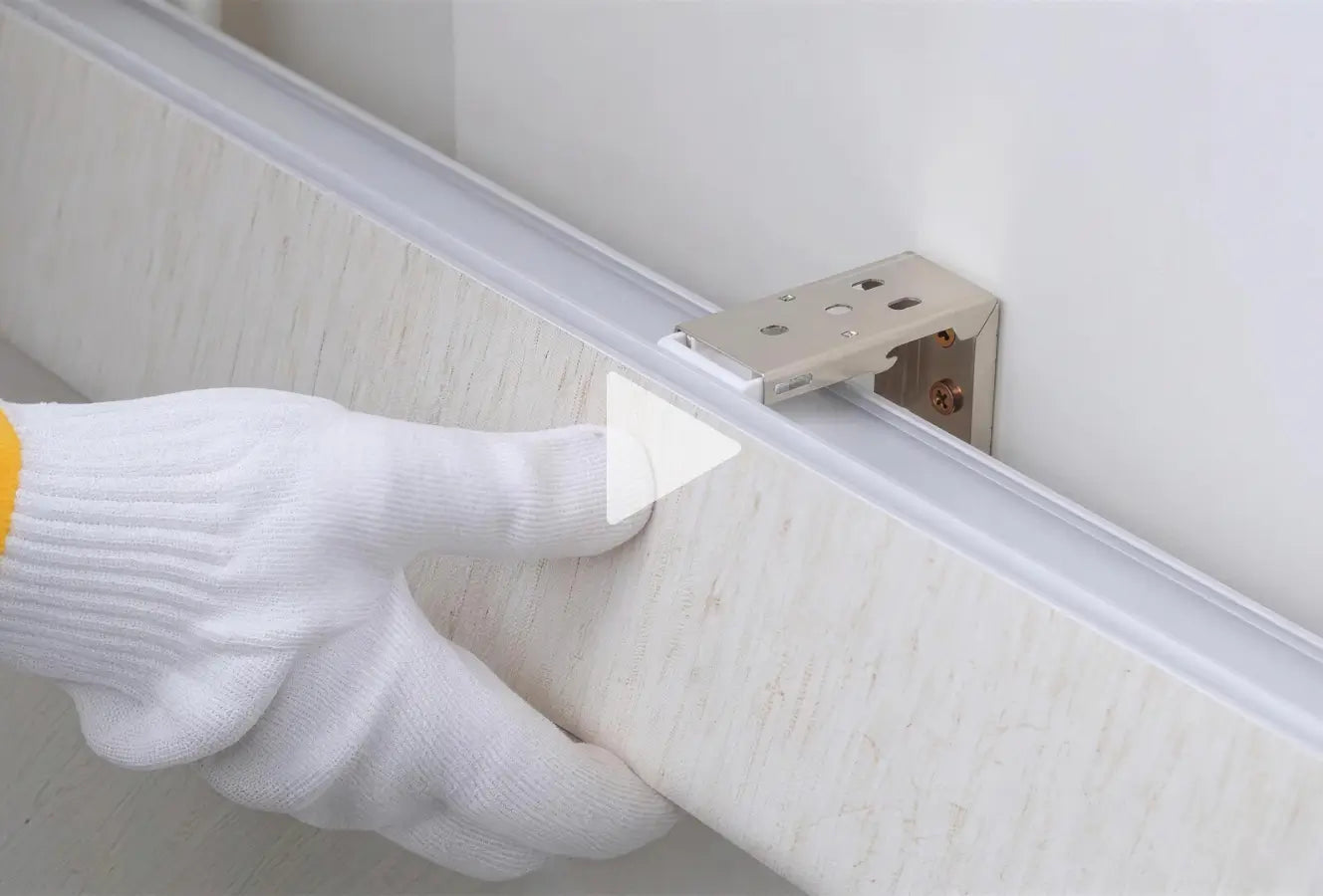 Translation missing: en.Hand wearing a white glove installing a metal bracket on a wall