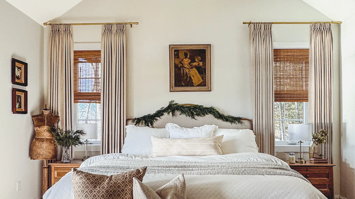 Linen-blend curtains layered with woven wood shades in a cream bedroom
