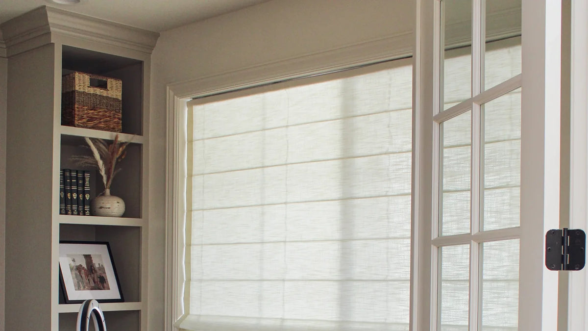 Cream linen-blend roman shade on a window beside a French door in a home office