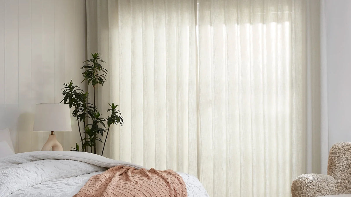 Bed in front of a wall of light-filtering cream curtains hung from the ceiling