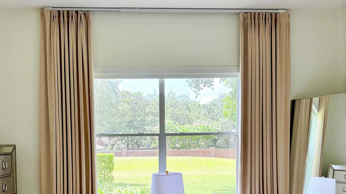 Window with a light-colored shade at the top and floor-length velvet curtains on either side