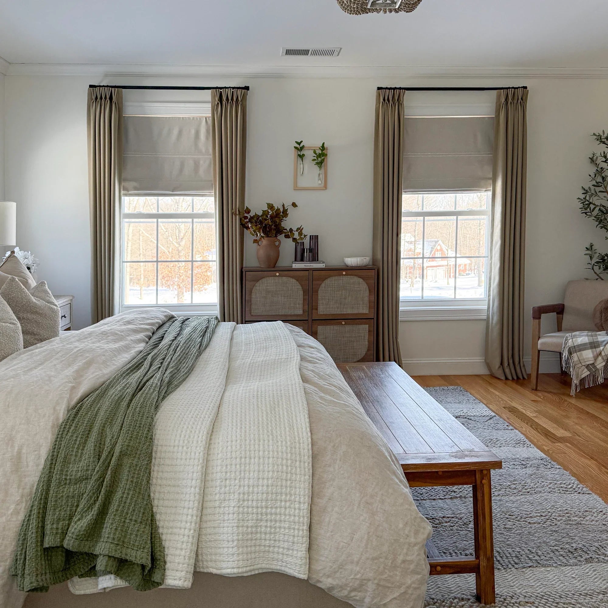 Warm-neutral 2026 designer bedroom with floor-to-ceiling off-white linen drapery and a woven-wood side-window shade