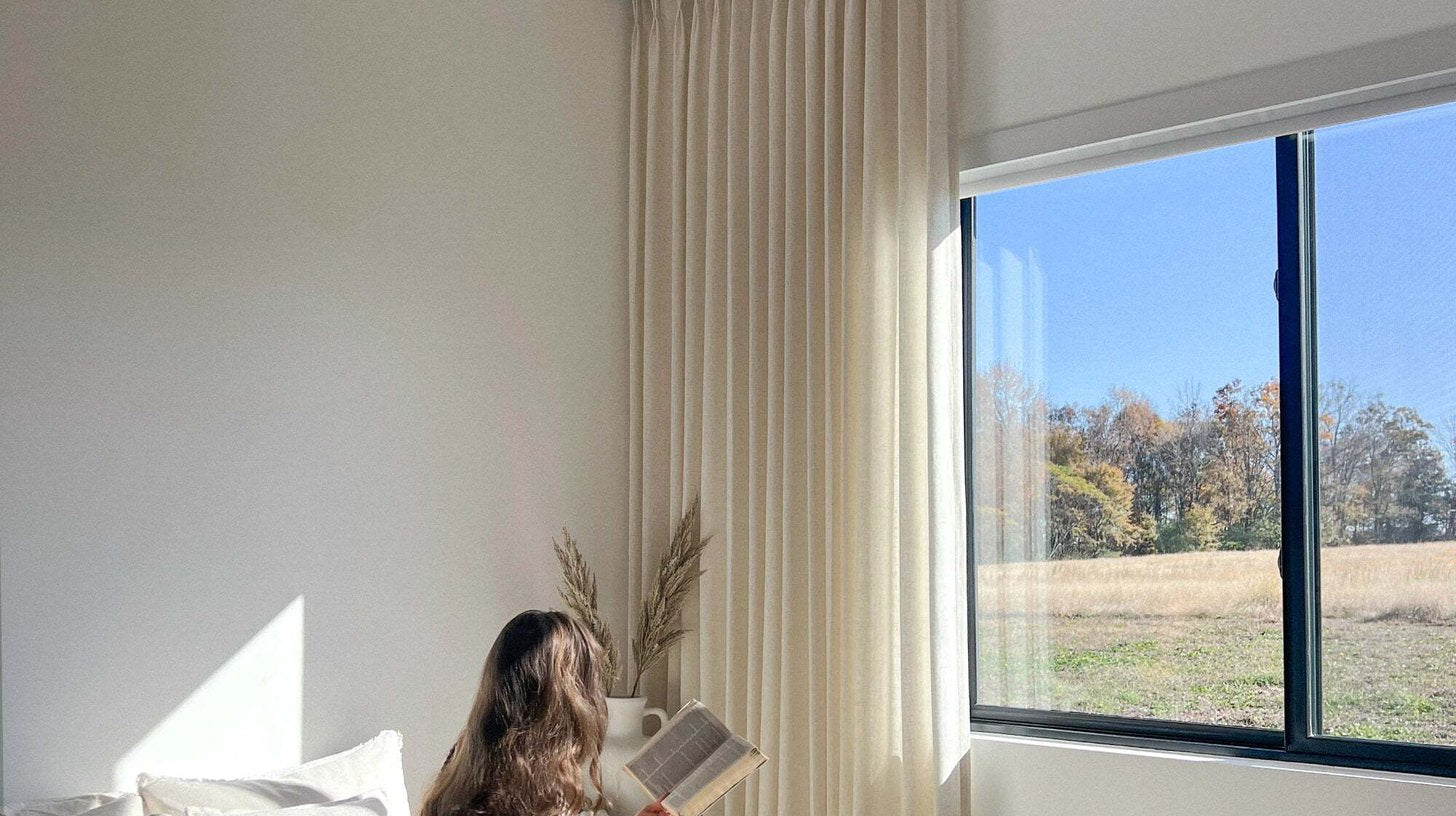 Soft cream linen-look curtains filtering daylight beside a bedroom window