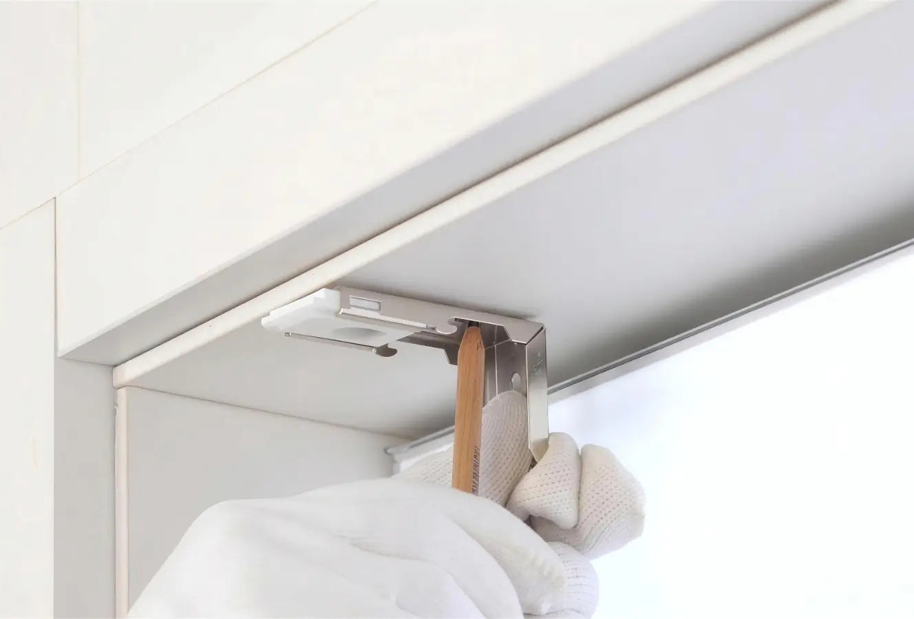 Clothing hanger attached to a white cabinet with a neutral background