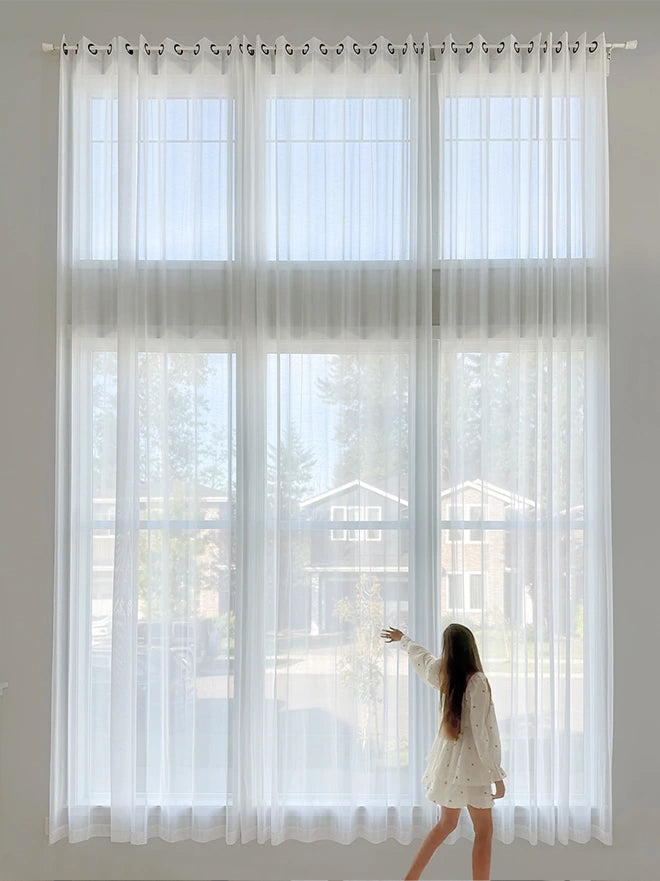 See through sheer curtains softly filtering light, creating a bright and airy ambiance.