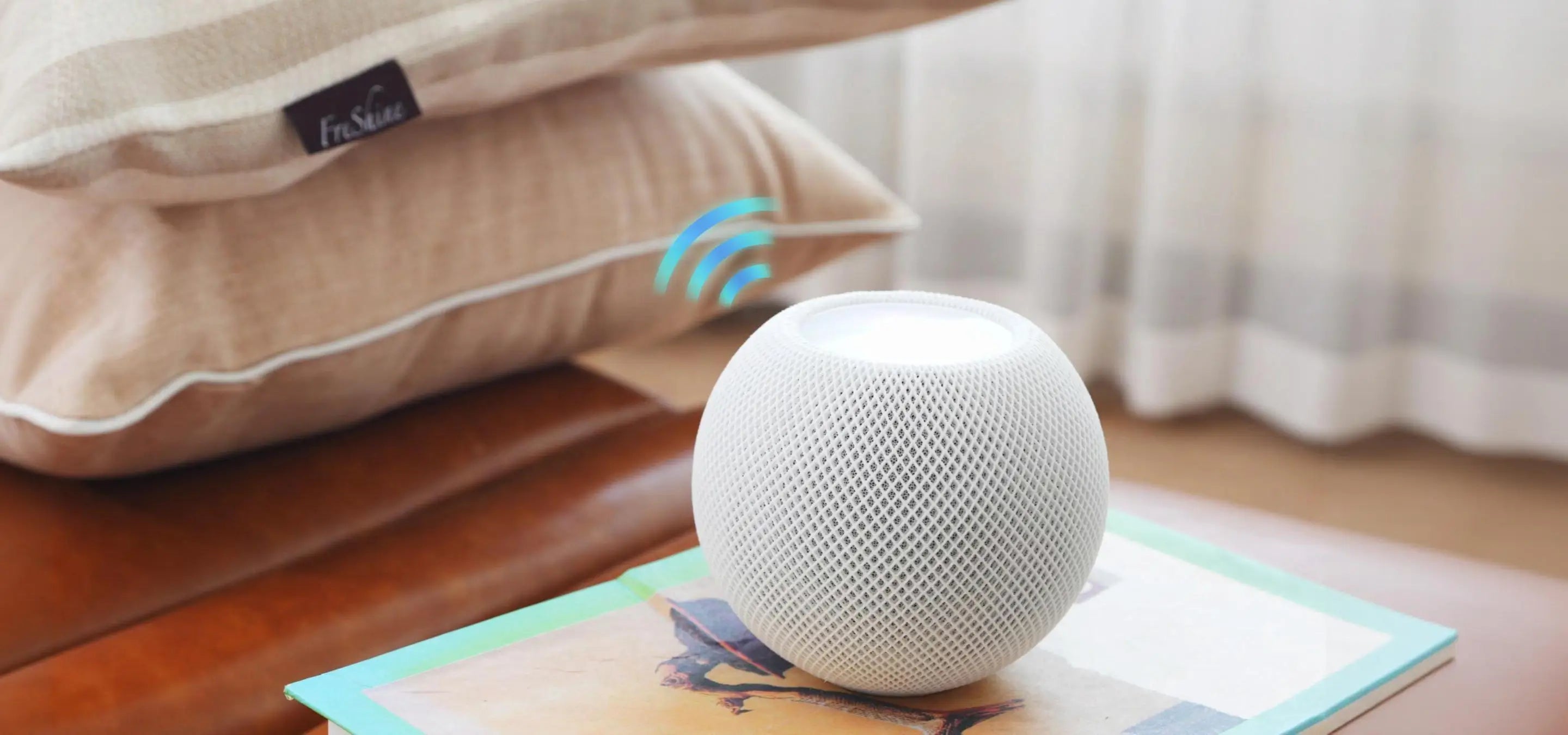 White smart speaker on a surface with pillows and a blanket in the background